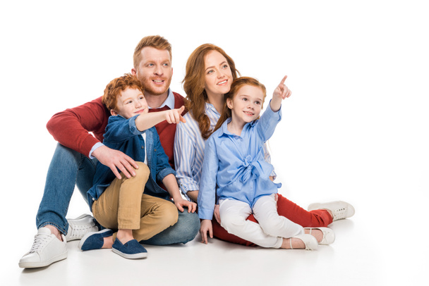 smiling family with two kids pointing away with fingers isolated on white - Valokuva, kuva