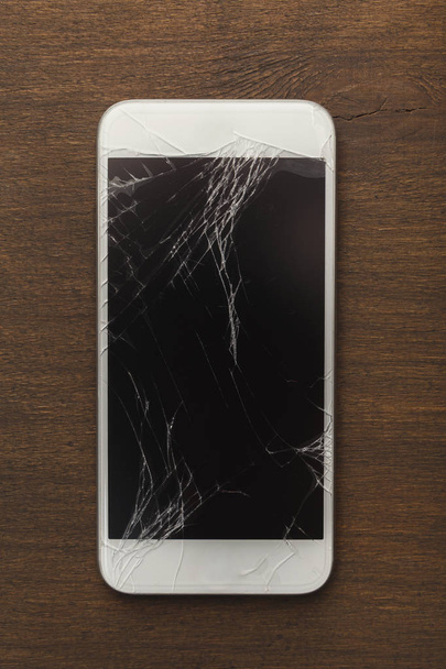 Сломанный смартфон на деревянном столе
 - Фото, изображение