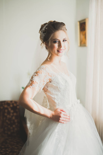 Gorgeous bride in robe posing and preparing for the wedding ceremony face in a room - Valokuva, kuva