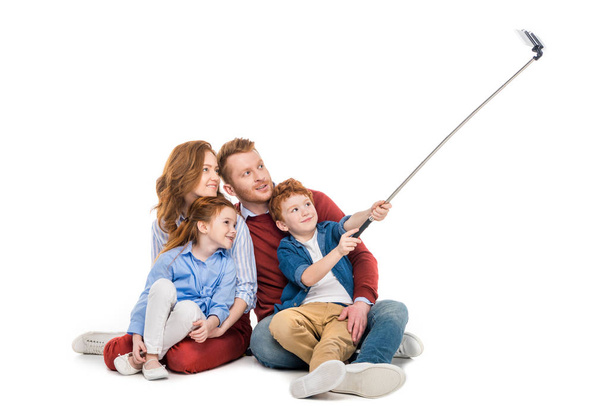 happy red haired family sitting together and taking selfie with smartphone isolated on white - Foto, imagen