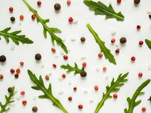 Κορνίζα πράσινη ρόκα φύλλα με κόκκινο και μαύρο πιπέρι λευκό φόντο αντίγραφο χώρου - Φωτογραφία, εικόνα