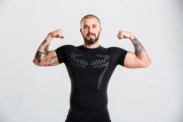 Portrait of strong man in black sportswear with tattoo on his ar - Zdjęcie, obraz