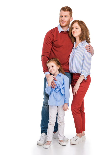 happy redhead family with one kid standing together and looking away isolated on white  - Foto, afbeelding