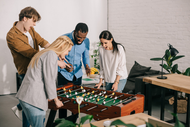 businesswomen playing table football and two male colleagues pointing on board game - Фото, изображение