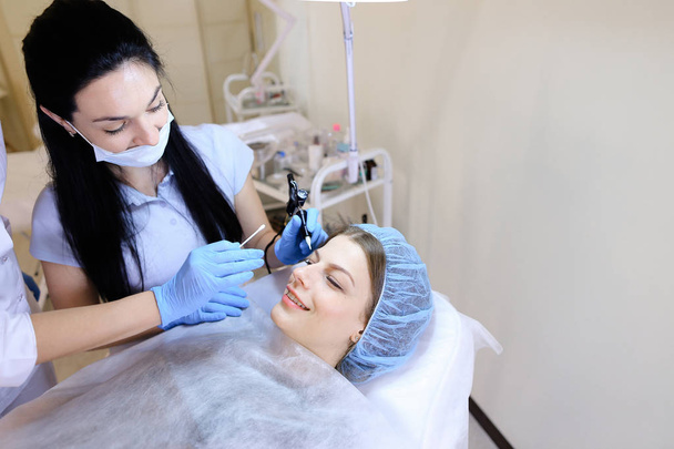 Kosmetolog Dokonywanie oznaczanie procedury dla kobiety przez maszyny. - Zdjęcie, obraz