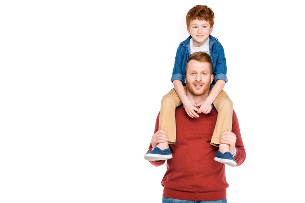 cute little boy sitting on neck of happy father and smiling at camera isolated on white - Photo, Image