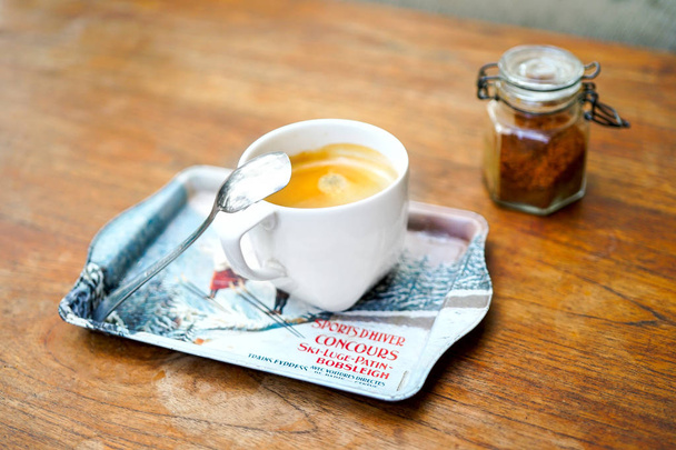 A cup of coffee on a wooden table. A fragrant drink with a teaspoon of foam and brown sugar. A metal tray in the form of a stand. Blurred background, top and side view with copy space. - Photo, Image