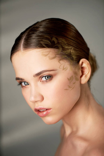 On the face pattern gold, sprayed through a stencil. Clear skin.Beauty shooting,Portrait of young beautiful girl in Studio, with professional makeup.Beauty shooting. - Foto, Imagen