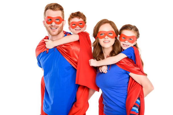 super parents piggybacking happy kids in masks and cloaks isolated on white - Фото, зображення