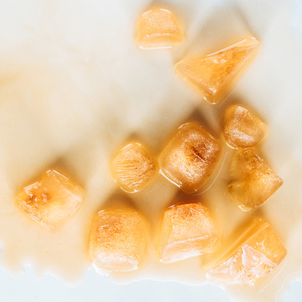 bovenaanzicht van bruin ijsblokjes gemaakt van koffie op witte tafelblad - Foto, afbeelding