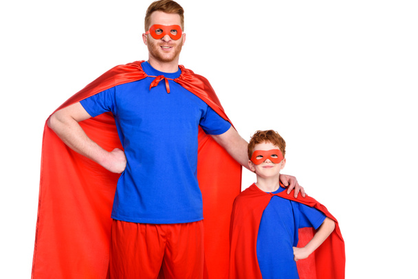 super father and son in masks and cloaks standing together and smiling at camera isolated on white - 写真・画像