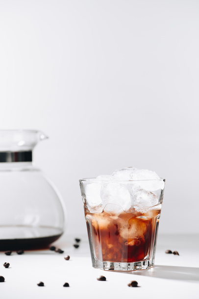 lähikuva lasi kylmää kahvia, kahvinkeitin ja paahdettuja kahvipapuja harmaalla pohjalla
 - Valokuva, kuva