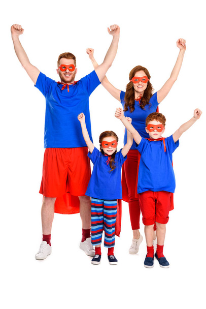 Gelukkig super familie in kostuums verhogen handen en lachend op camera geïsoleerd op wit - Foto, afbeelding