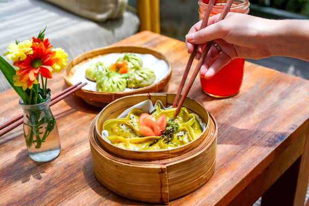 Asperges tofu knoedel - close-up. Voedsel sticks en Chinees eten. Op een houten tafel met bloemen en hand. Macro. Bovenaanzicht met kopie ruimte - Foto, afbeelding