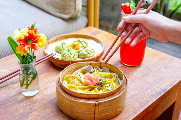 Спаржа тофу dumpling - великим планом. Палички для їжі та китайської кухні. На дерев'яну столову з квітами і руку. Макрос. Вид зверху з копією простір - Фото, зображення