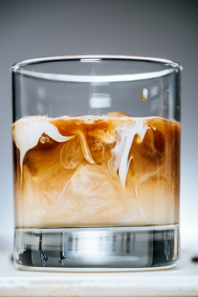 Nahaufnahme von kaltem Eiskaffee mit Milch im Glas auf grauem Hintergrund - Foto, Bild