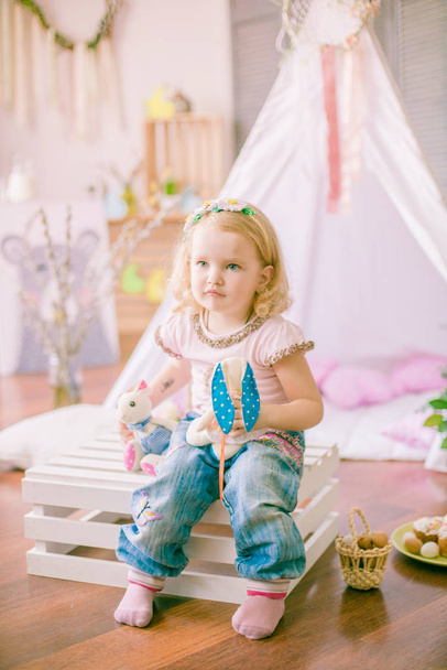  little cute girl are preparing for Easter celebration.  Child having fun with Easter decoration sitting on the floor at home. - Foto, imagen