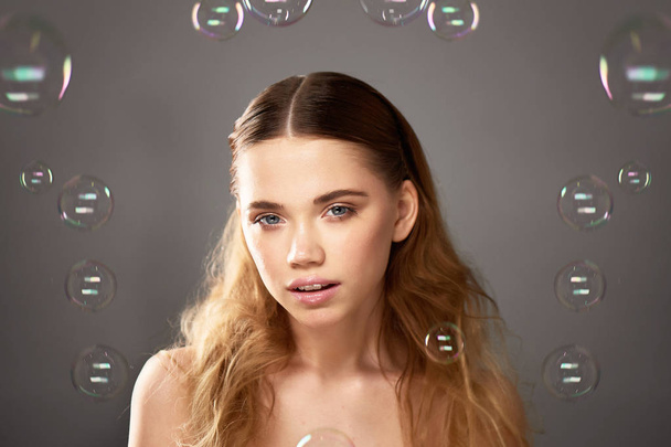 Portrait of young beautiful girl in Studio, with professional makeup.Beauty shooting.The beauty of soap bubbles. The rainbow flares - Photo, image