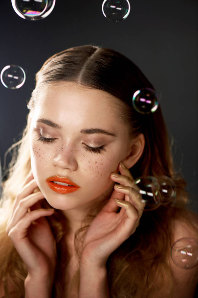 Portrait of young beautiful girl in Studio, with professional makeup.Beauty shooting.The beauty of soap bubbles. The rainbow flares - Foto, afbeelding