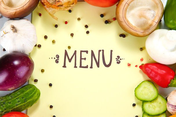 menu omgeven door producten en groenten op geel papier - Foto, afbeelding