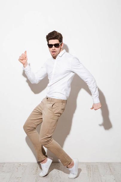 Full length photo of positive guy in shirt and trousers dancing  - Foto, Imagem