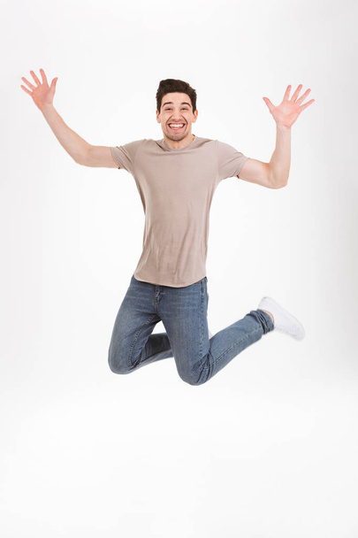 Full-length photo of excited man 30s in casual t-shirt and jeans - Фото, изображение