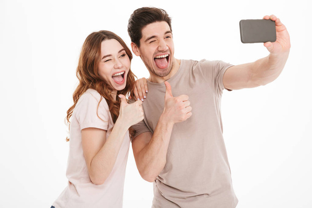 Portrait of a cheerful young couple showing thumbs up - Foto, imagen