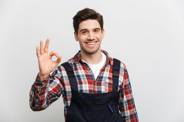 Smiling male builder showing ok sign and looking at camera - Foto, imagen