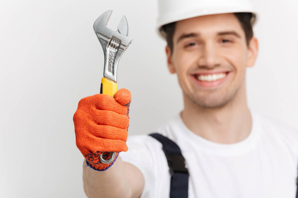 Smiling male builder showing wrench at the camera - Fotografie, Obrázek