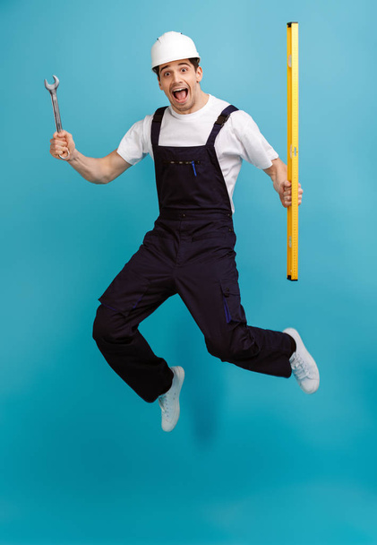 Full length image of Happy screaming male builder holding rench - Фото, изображение