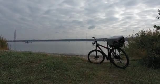 Bisiklet nehir kıyısında duruyor. Akşam nehir genişlik üzerinde bir manzara olduğunu - Video, Çekim