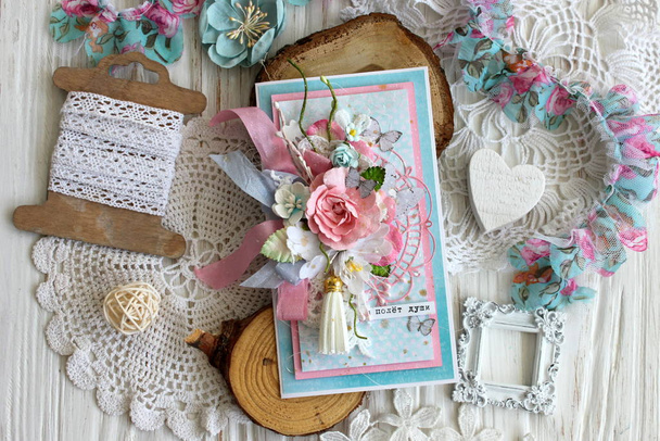 Um cartão feito à mão com flores, fitas e um borla de camurça em rosa e azul
 - Foto, Imagem