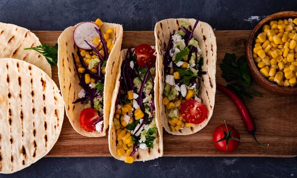 Pulled pork tacos with red cabbage, tomatoes, corn, feta and avocados overhead shot. - Foto, imagen
