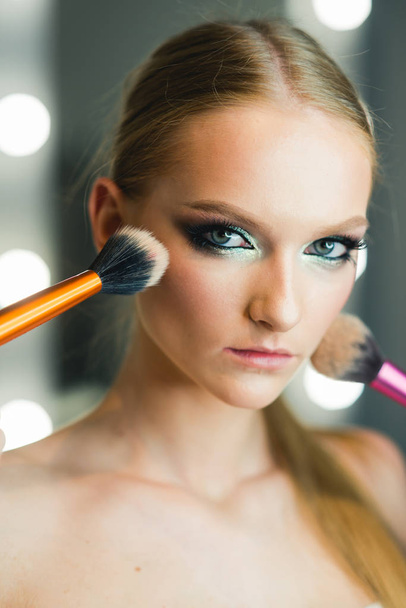 Girl makeup face with powder brushes in beauty salon. Girl skin, skincare, cosmetics. - Photo, Image