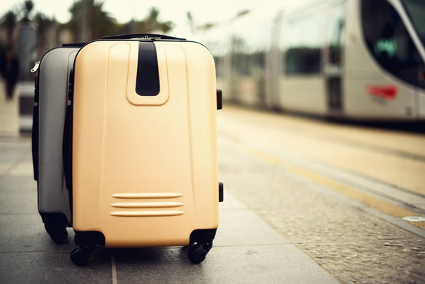 Two suitcases standing on railway station against city train. Vacation and travel concept. Citypass Light Rail in Jerusalem. Copy space, selective focus - Foto, Bild