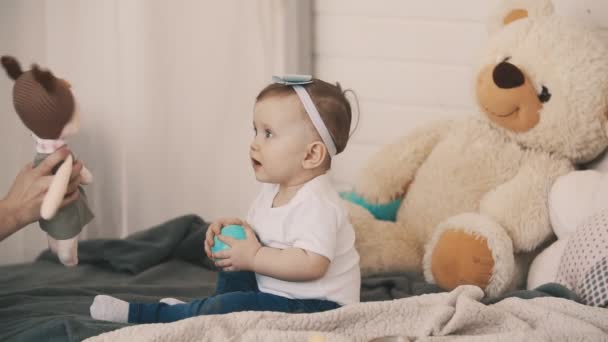 Young mother and daughter having fun in bedroom with soft toy in slow motion - Materiał filmowy, wideo