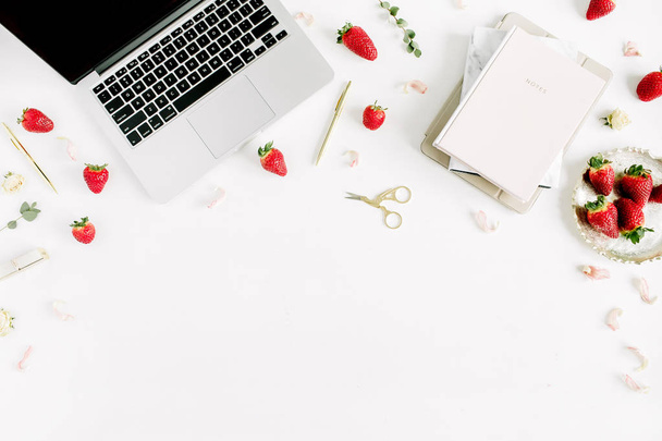 Workspace with laptop, notebook, strawberry, petals and eucalyptus branches on white background. Flat lay, top view minimal blog hero header. - Photo, Image