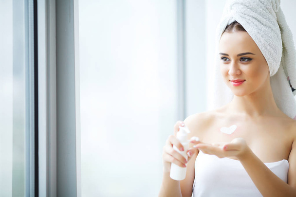 Parfait jeune femme appliquant la crème faciale dans la salle de bain
 - Photo, image