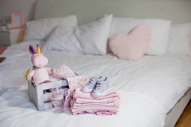 Zapatos y ropa para niños en la cama. Hermosa ropa de bebé rosa. Recién nacido. Comodidad en casa. Bebé.
. - Foto, Imagen