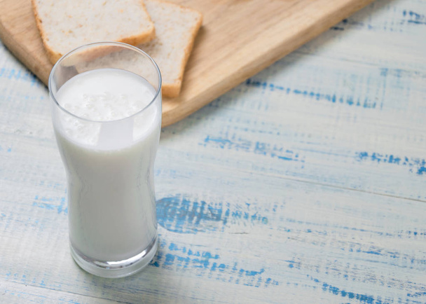 Kefir, yogurt in a glass on a background of slices of white bread on a wooden background. - Fotoğraf, Görsel