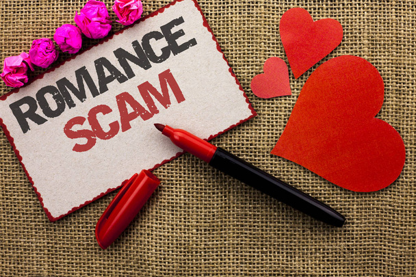 Word writing text Romance Scam. Business concept for Dating Cheat Love Embarrassed Fraud Cyber Couple Affair written on Cardboard Piece on the jute background Marker and Hearts next to it. - Photo, Image