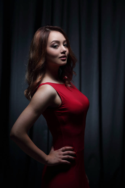 Girl in a red dress on a dark background - 写真・画像