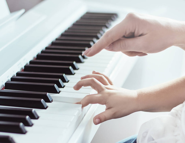 Closeup picture of two hands playing piano - Foto, afbeelding