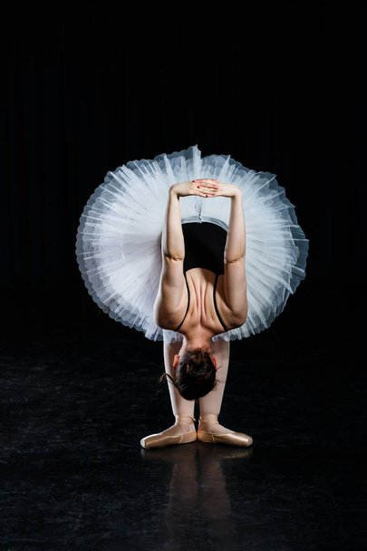 Girl ballerina posing and performing dance elements in bright scenic light on a black background - Foto, immagini