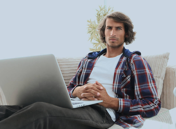 serious guy with laptop sitting on sofa - Фото, изображение