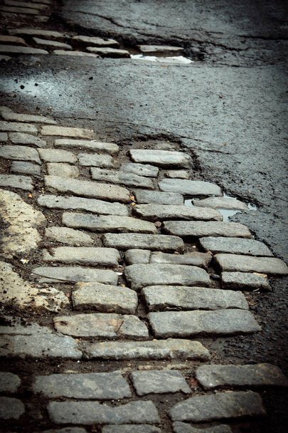 Old New York City cobblestone street repaired with asphalt - Foto, afbeelding