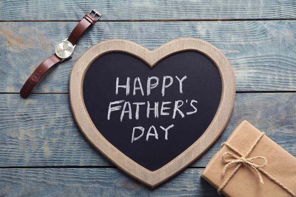 Gift box, watch and chalkboard with words HAPPY FATHER'S DAY on wooden background, top view - Foto, Imagem