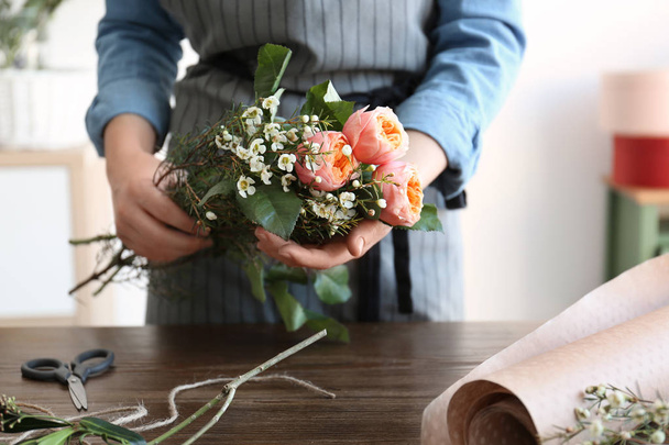 Female florist creating beautiful bouquet at table - Фото, изображение