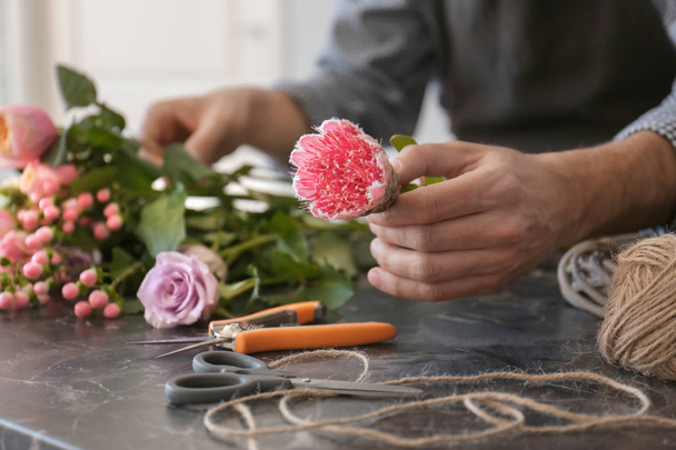 Male florist creating beautiful bouquet at table, closeup - Foto, afbeelding