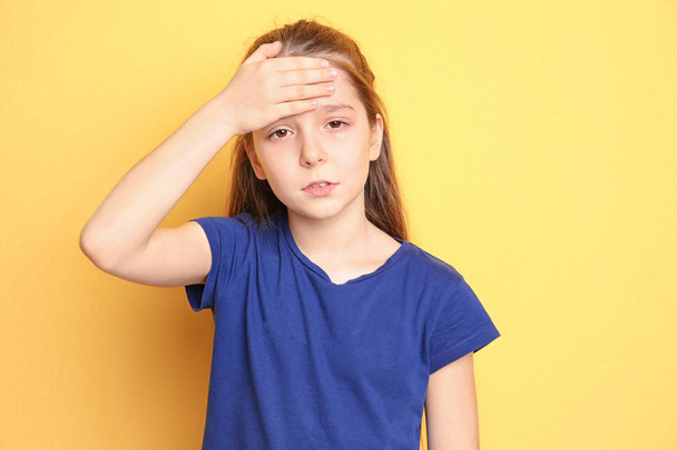 Little girl suffering from headache on color background - Foto, immagini